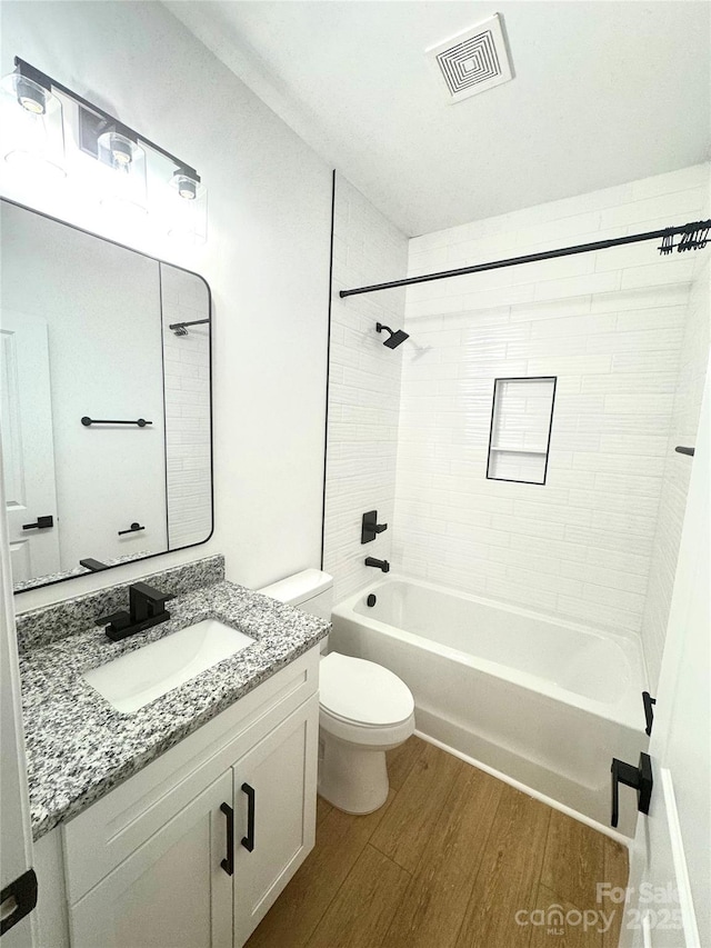 full bathroom featuring toilet, vanity, hardwood / wood-style floors, and tiled shower / bath