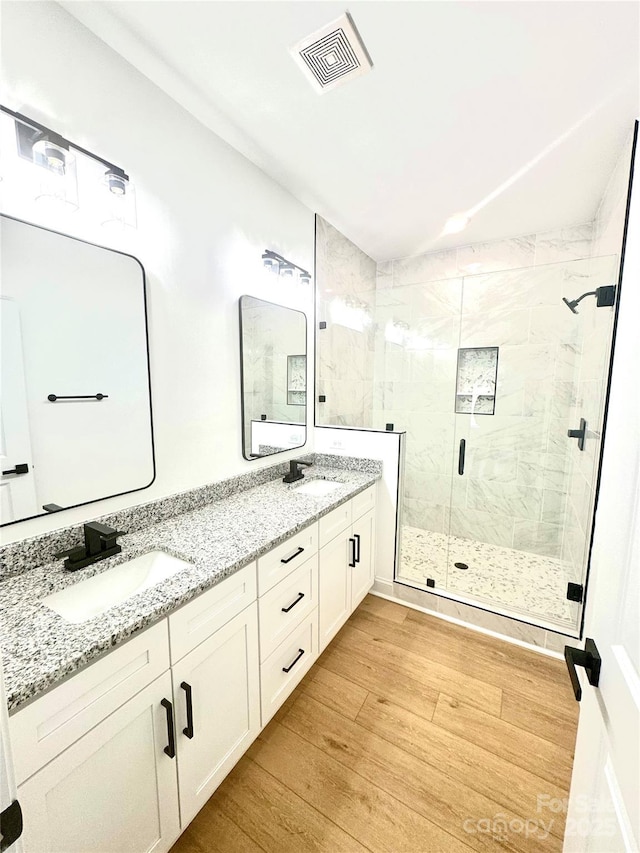 bathroom with hardwood / wood-style flooring, an enclosed shower, and vanity