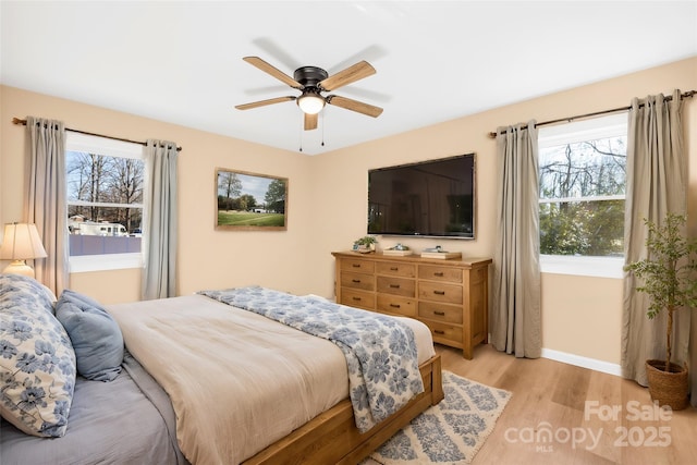 bedroom with a ceiling fan, multiple windows, baseboards, and light wood-type flooring