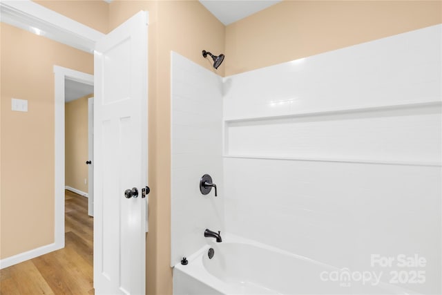 bathroom featuring baseboards, shower / tub combination, and wood finished floors