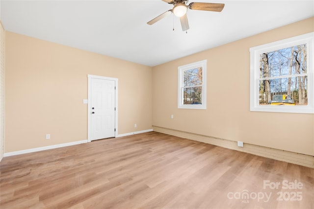 empty room with a wealth of natural light, ceiling fan, light wood-type flooring, and baseboards