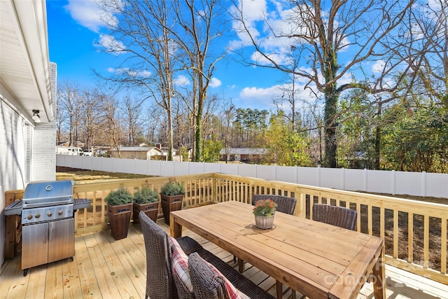 wooden terrace with area for grilling, outdoor dining area, and a fenced backyard