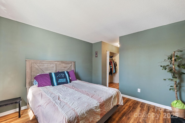 bedroom with a closet, a walk in closet, and hardwood / wood-style flooring