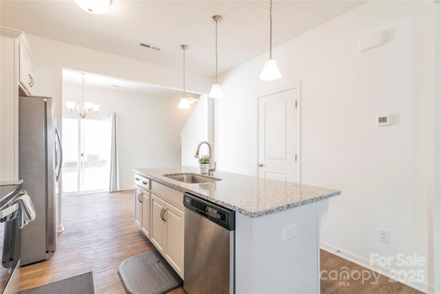 kitchen with light stone countertops, white cabinets, appliances with stainless steel finishes, an island with sink, and sink