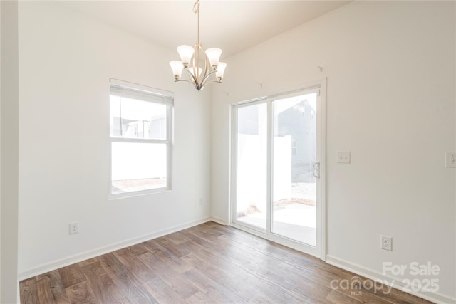 unfurnished room featuring a notable chandelier, a healthy amount of sunlight, and wood-type flooring