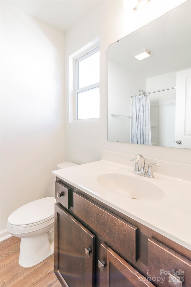 bathroom featuring wood-type flooring, toilet, vanity, and a shower with curtain