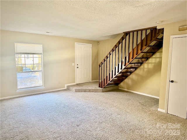 carpeted foyer featuring a textured ceiling