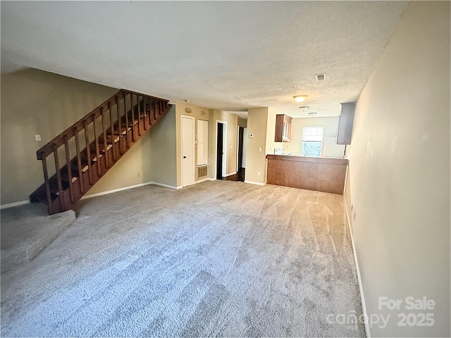 unfurnished living room featuring carpet and a textured ceiling