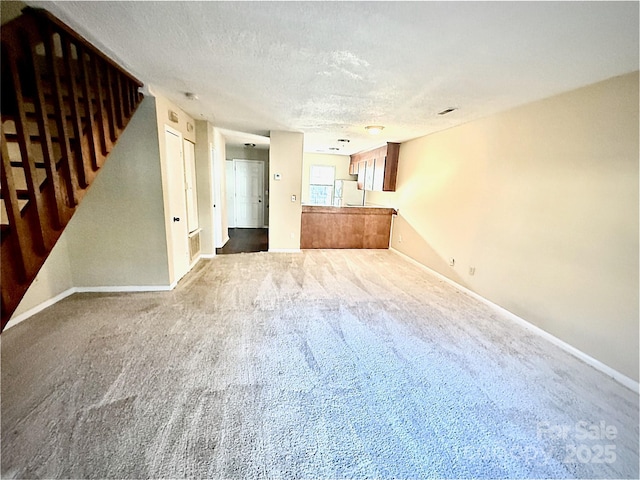 unfurnished living room with carpet floors and a textured ceiling