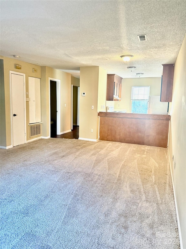 unfurnished living room featuring a textured ceiling and carpet flooring