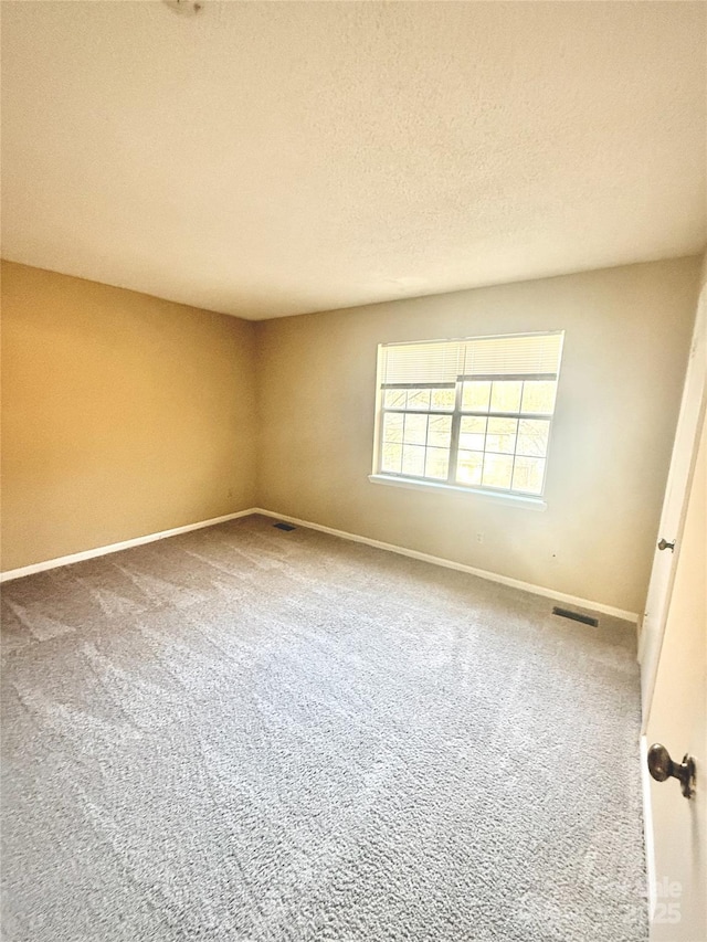 carpeted empty room with a textured ceiling