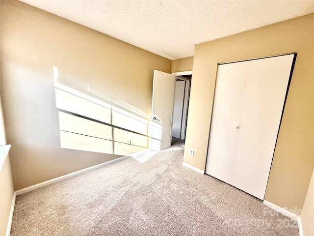 unfurnished bedroom featuring light carpet, a closet, and a textured ceiling