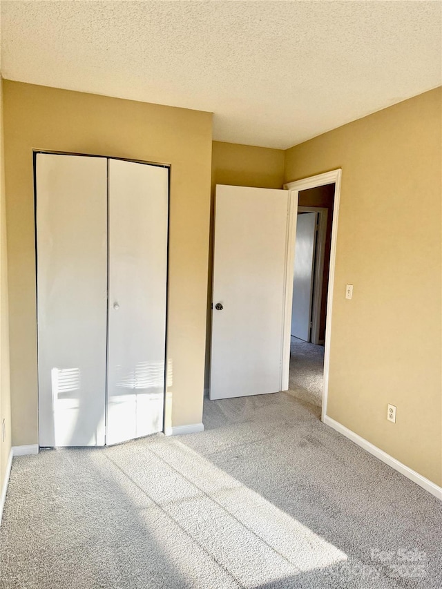 unfurnished bedroom featuring carpet floors, a closet, and a textured ceiling