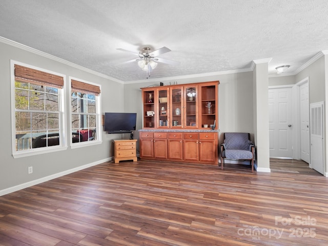 living area featuring a textured ceiling, ceiling fan, crown molding, and dark wood-type flooring