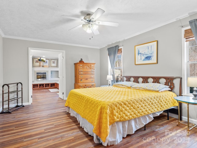 bedroom with a textured ceiling, ceiling fan, crown molding, and hardwood / wood-style flooring