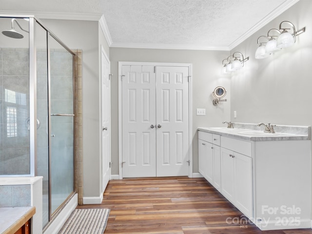 bathroom featuring a textured ceiling, crown molding, an enclosed shower, and vanity