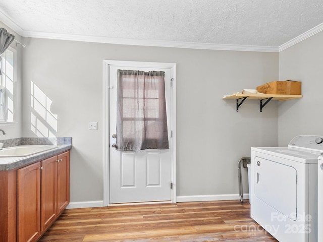 laundry area with a textured ceiling, sink, ornamental molding, independent washer and dryer, and light wood-type flooring