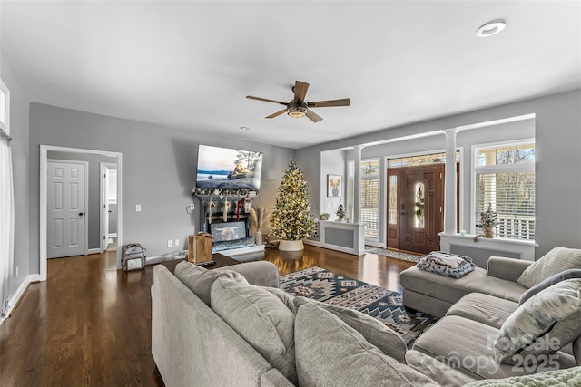 living room with dark hardwood / wood-style flooring, a fireplace, decorative columns, and ceiling fan