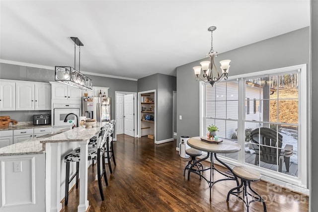 kitchen with white cabinetry, an island with sink, decorative light fixtures, and stainless steel fridge with ice dispenser