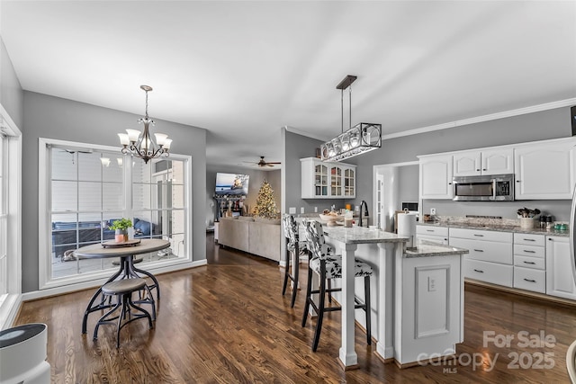 kitchen with ceiling fan with notable chandelier, decorative light fixtures, a center island, and white cabinets