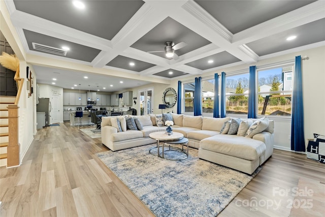 living room with beamed ceiling, crown molding, and light wood-type flooring