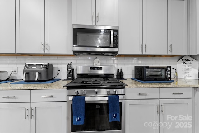 kitchen with backsplash, stainless steel appliances, and white cabinets