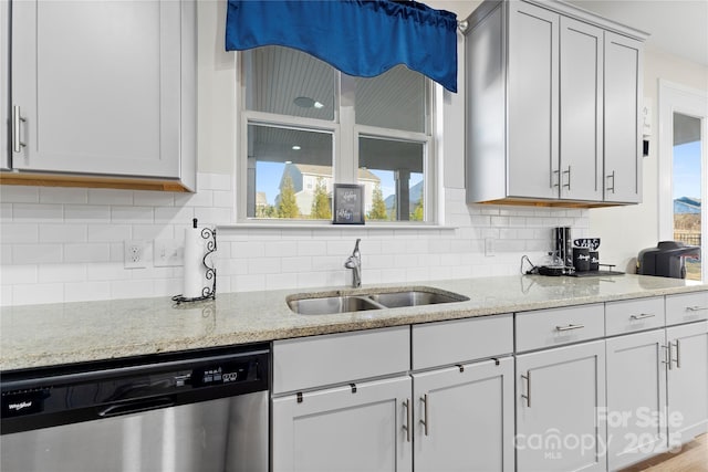 kitchen with dishwasher, light stone countertops, sink, and a healthy amount of sunlight