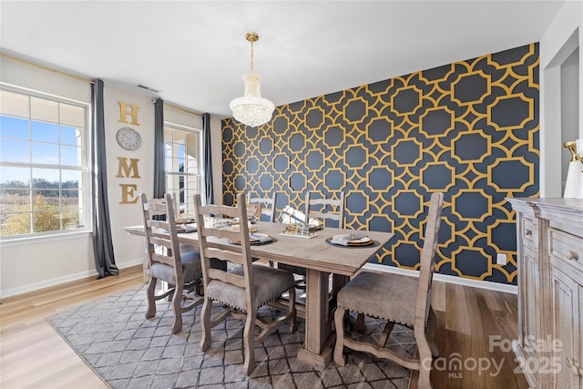 dining space with light hardwood / wood-style floors and a chandelier