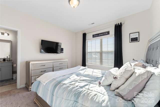 bedroom featuring light colored carpet and ensuite bath