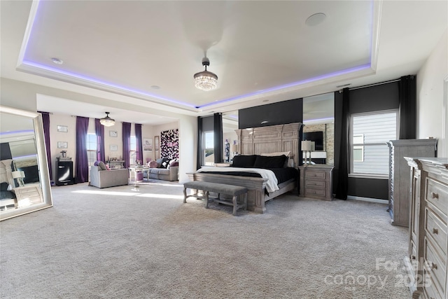 carpeted bedroom featuring multiple windows and a tray ceiling