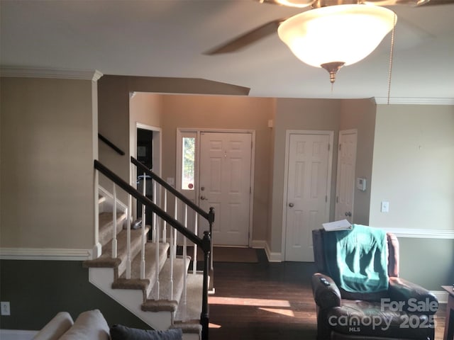 foyer entrance featuring baseboards, stairway, crown molding, and wood finished floors