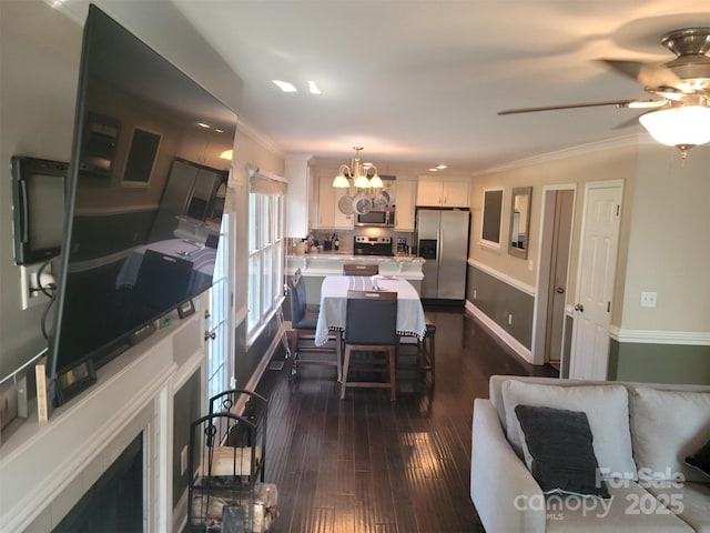 interior space with dark wood-type flooring, crown molding, and ceiling fan with notable chandelier