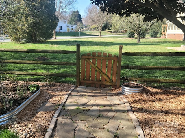 view of gate with fence and a lawn