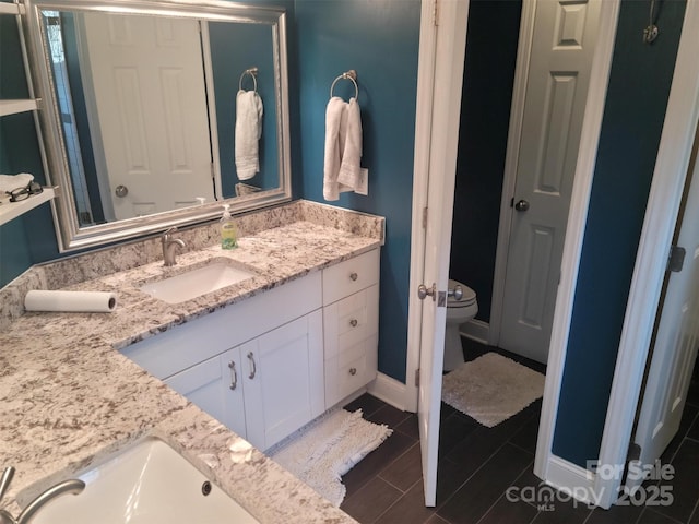 bathroom featuring toilet, baseboards, and vanity