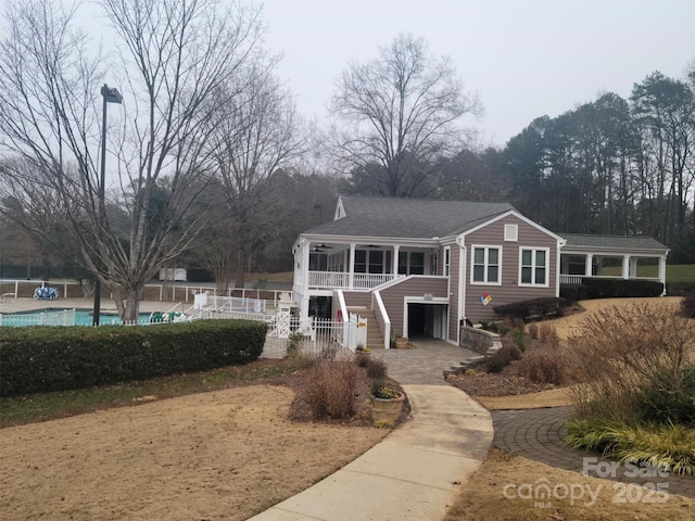 view of front of property with stairs, covered porch, fence, and a fenced in pool