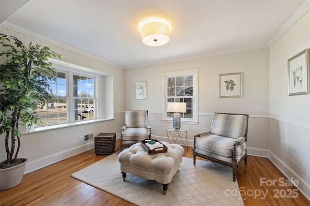 living area with light wood-style floors, visible vents, crown molding, and baseboards