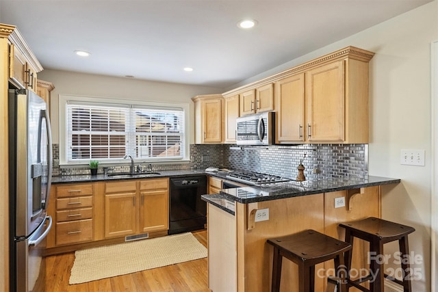 kitchen with a peninsula, appliances with stainless steel finishes, a breakfast bar area, and a sink