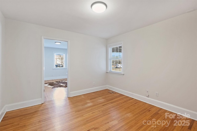 spare room featuring baseboards, visible vents, and light wood-style floors