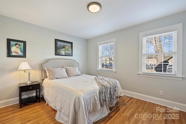 bedroom featuring visible vents, baseboards, and wood finished floors