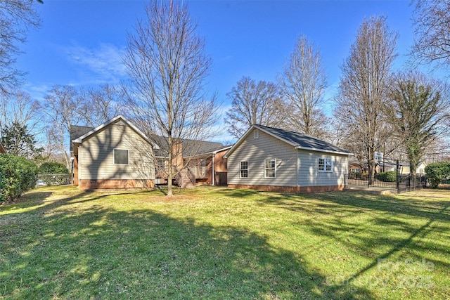 back of property with crawl space, a lawn, and fence