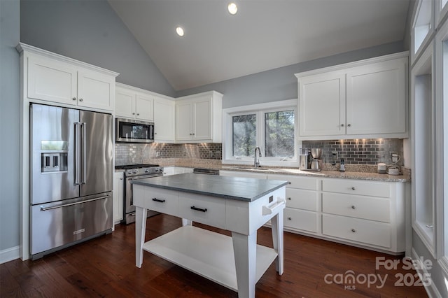 kitchen with premium appliances, white cabinetry, dark hardwood / wood-style flooring, decorative backsplash, and sink