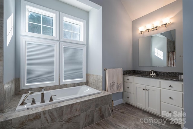 bathroom featuring tiled bath, vanity, and lofted ceiling