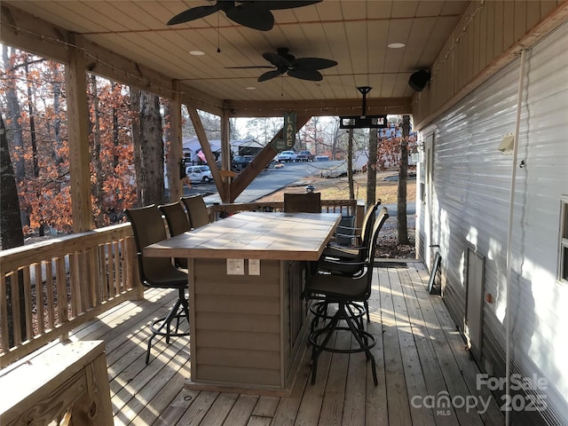 deck featuring ceiling fan and exterior bar