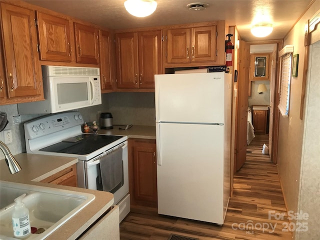 kitchen with dark hardwood / wood-style flooring, sink, and white appliances