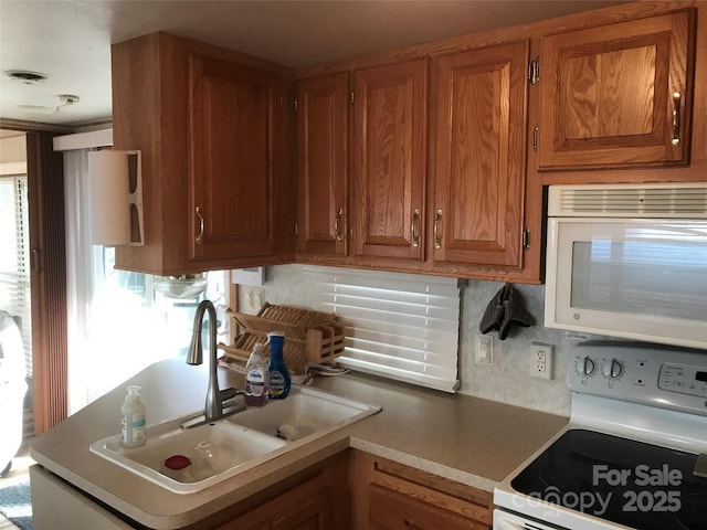 kitchen featuring white appliances, sink, and backsplash