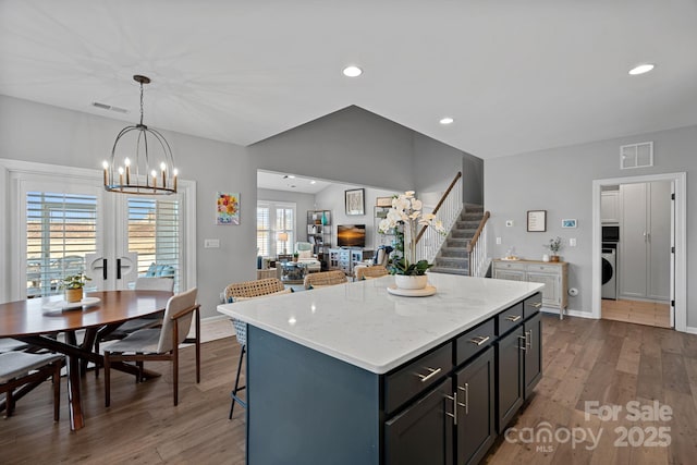 kitchen featuring a healthy amount of sunlight, dark wood-type flooring, pendant lighting, washer / clothes dryer, and a center island