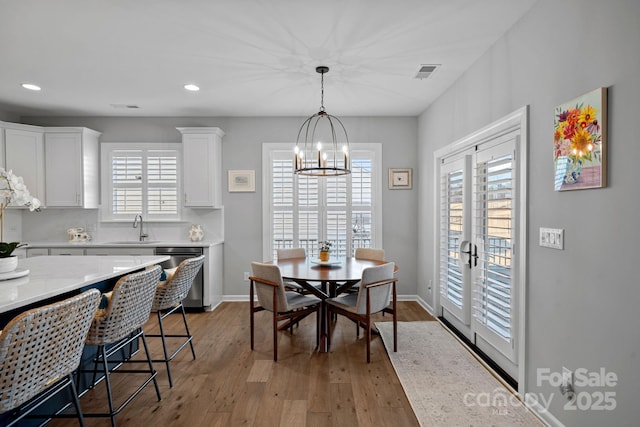 dining area with an inviting chandelier, a wealth of natural light, light hardwood / wood-style floors, and sink