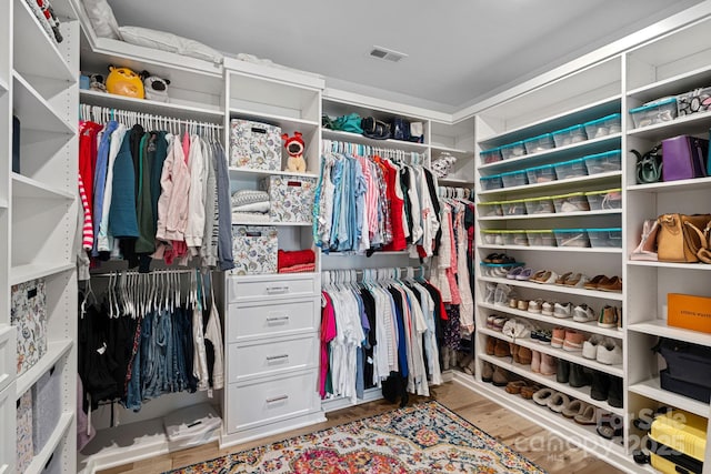 walk in closet with light hardwood / wood-style floors