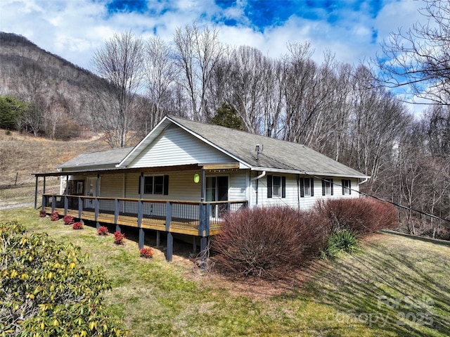 rear view of house featuring a yard, roof with shingles, and a wooden deck