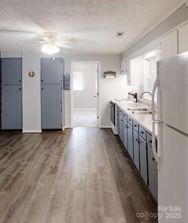 kitchen featuring a textured ceiling, light countertops, white appliances, and a sink